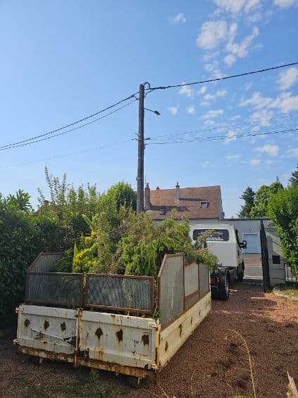 Benne chargée de branchages et de tailles de haies dans le jardin d'une maison