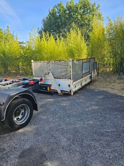 Benne ouverte livrée sur un terrain privé bordé d'arbres, prête à être remplie